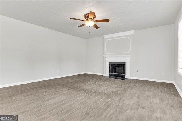 unfurnished living room with ceiling fan, light hardwood / wood-style floors, and a textured ceiling