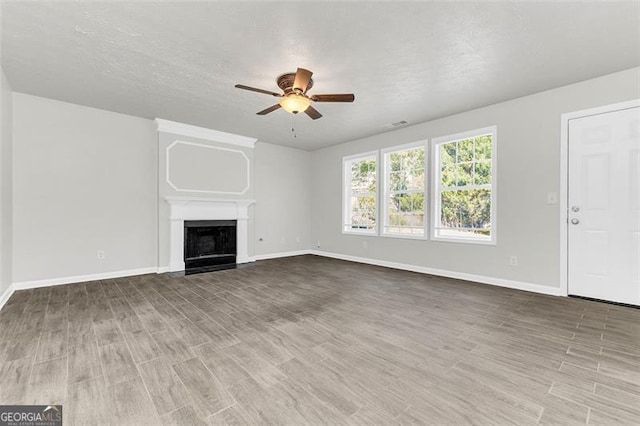 unfurnished living room with hardwood / wood-style flooring, ceiling fan, and a textured ceiling