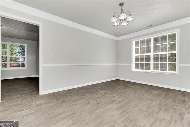 unfurnished room featuring wood-type flooring, an inviting chandelier, ornamental molding, and a textured ceiling