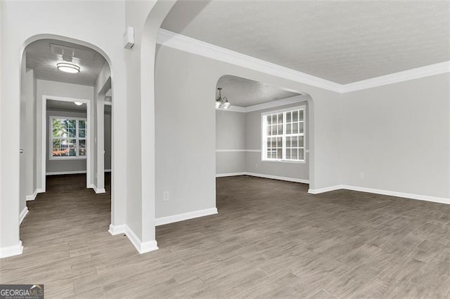 empty room with crown molding, hardwood / wood-style flooring, and a textured ceiling