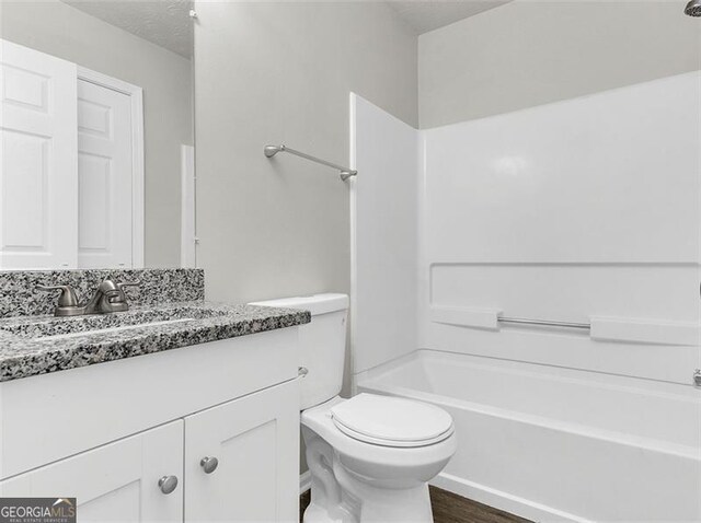 full bathroom with bathing tub / shower combination, wood-type flooring, vanity, and toilet