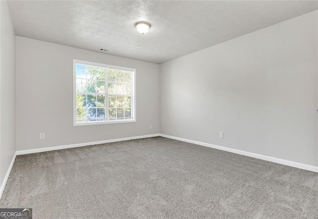 carpeted spare room with a textured ceiling