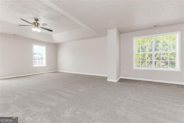 carpeted spare room featuring ceiling fan, a textured ceiling, and a raised ceiling