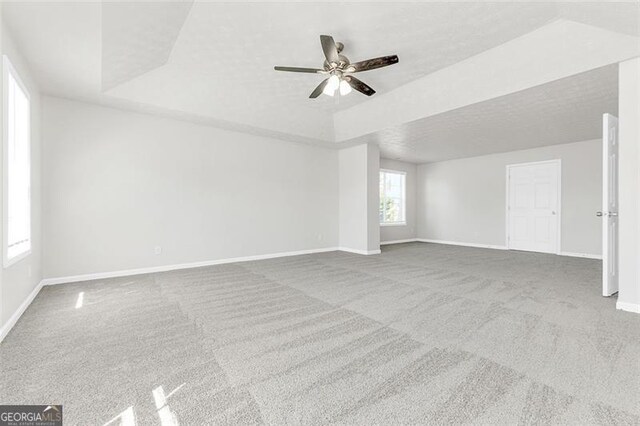 carpeted spare room with ceiling fan, a tray ceiling, and a textured ceiling