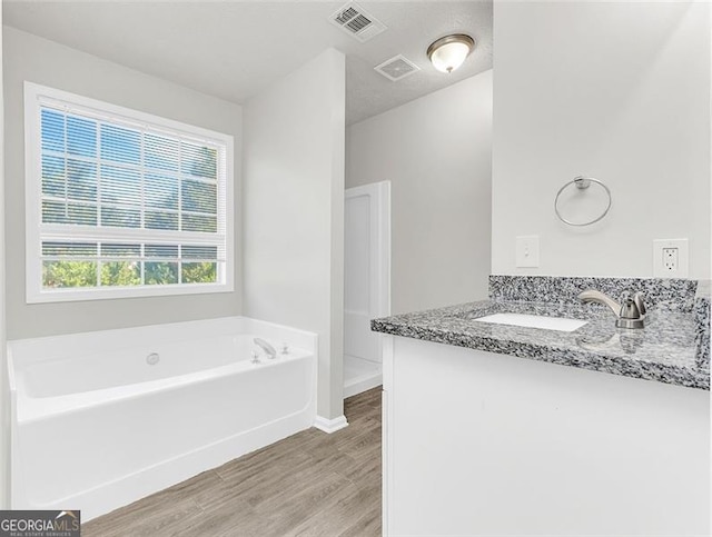 bathroom featuring a tub, hardwood / wood-style flooring, vanity, and a textured ceiling