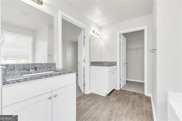 bathroom with wood-type flooring, a washtub, vanity, and a textured ceiling