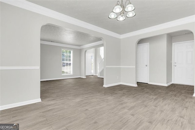 spare room featuring ornamental molding, a chandelier, hardwood / wood-style flooring, and a textured ceiling