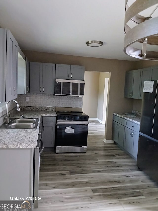 kitchen featuring decorative backsplash, stainless steel appliances, hardwood / wood-style flooring, sink, and gray cabinets