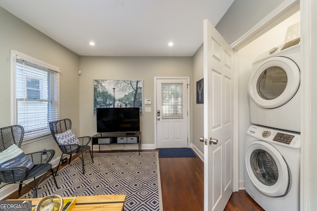 clothes washing area featuring stacked washer / dryer and dark hardwood / wood-style flooring