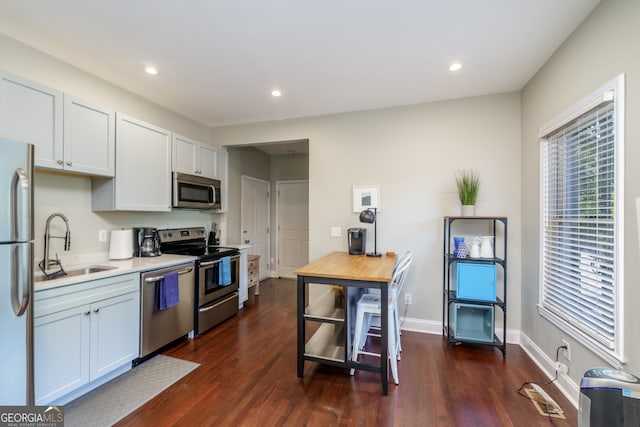 kitchen with appliances with stainless steel finishes, white cabinetry, sink, and dark hardwood / wood-style floors