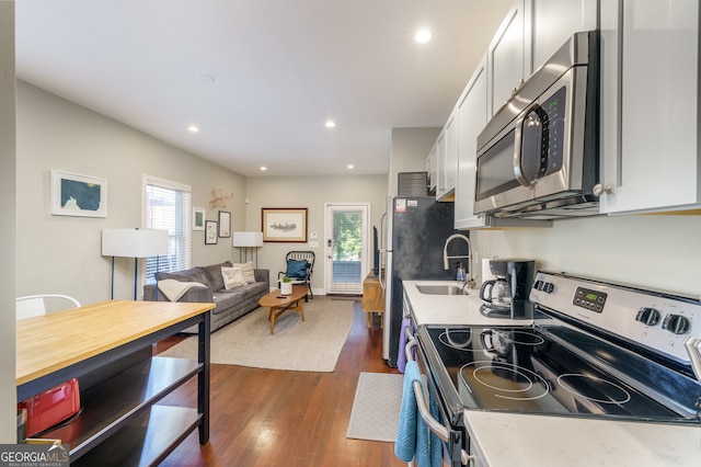 kitchen with stainless steel appliances, dark wood-type flooring, white cabinets, and sink