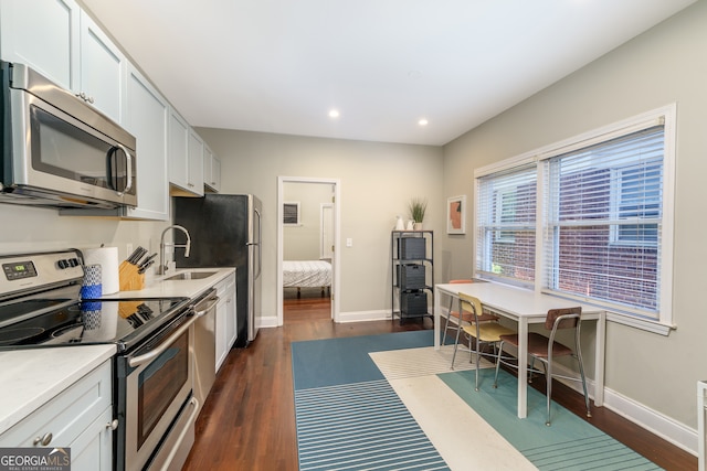 kitchen featuring appliances with stainless steel finishes, sink, dark hardwood / wood-style floors, and white cabinets