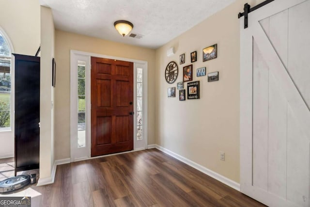 entrance foyer with a textured ceiling, a barn door, and dark hardwood / wood-style flooring