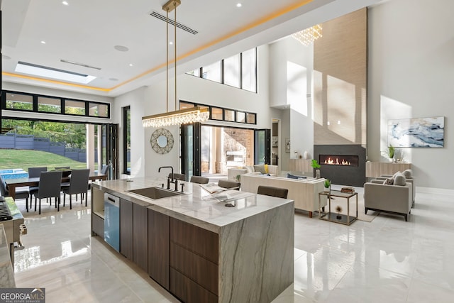 kitchen featuring sink, a wealth of natural light, an island with sink, and dishwasher