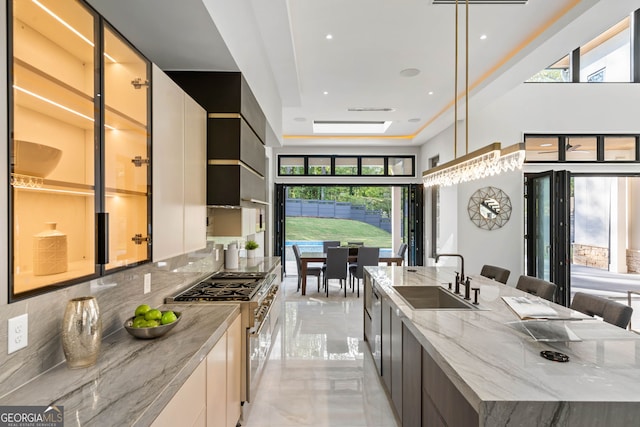 kitchen featuring hanging light fixtures, sink, plenty of natural light, and stainless steel stove