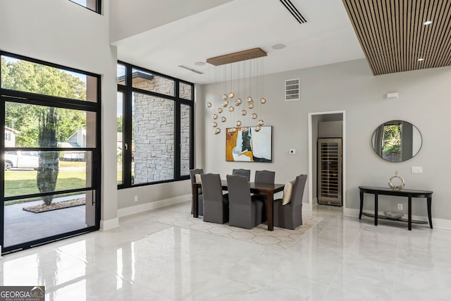 dining space with wine cooler and a towering ceiling