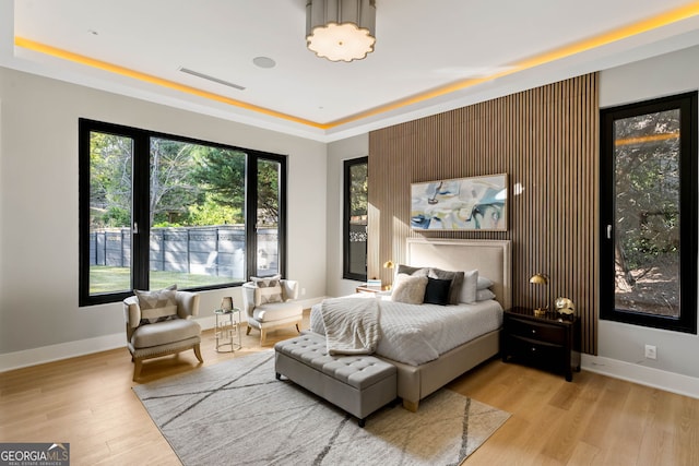 bedroom with a tray ceiling and light hardwood / wood-style flooring