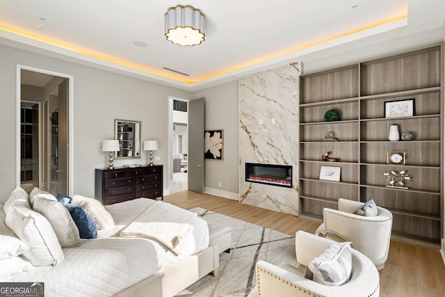 living room featuring light hardwood / wood-style floors, a raised ceiling, and a high end fireplace