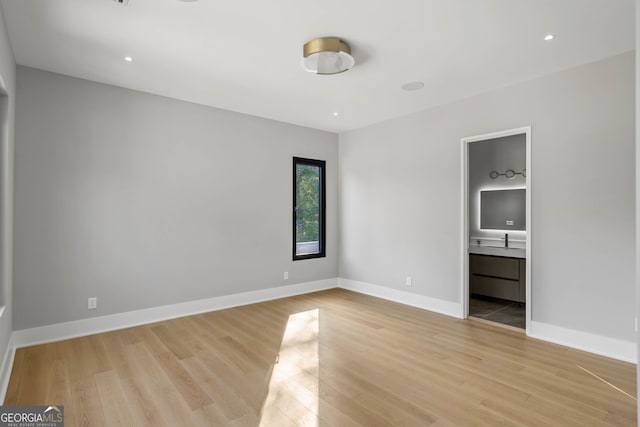 unfurnished bedroom featuring light hardwood / wood-style floors, ensuite bathroom, and sink