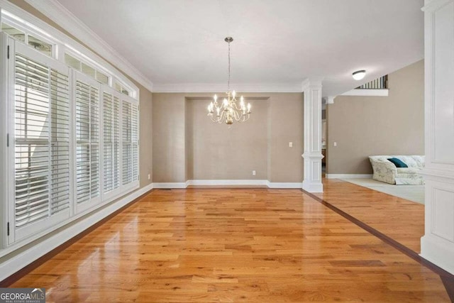 unfurnished dining area featuring ornamental molding, decorative columns, an inviting chandelier, and light hardwood / wood-style flooring