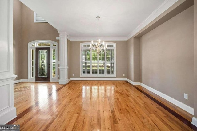 unfurnished dining area featuring a notable chandelier, light wood-style flooring, baseboards, ornamental molding, and ornate columns