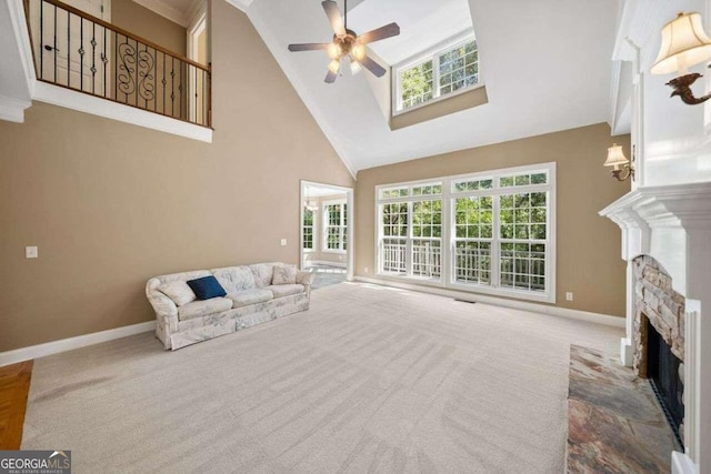 carpeted living room with ceiling fan, a fireplace, crown molding, and high vaulted ceiling