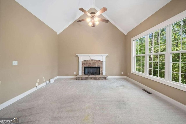 unfurnished living room featuring high vaulted ceiling, ceiling fan, a stone fireplace, and light colored carpet