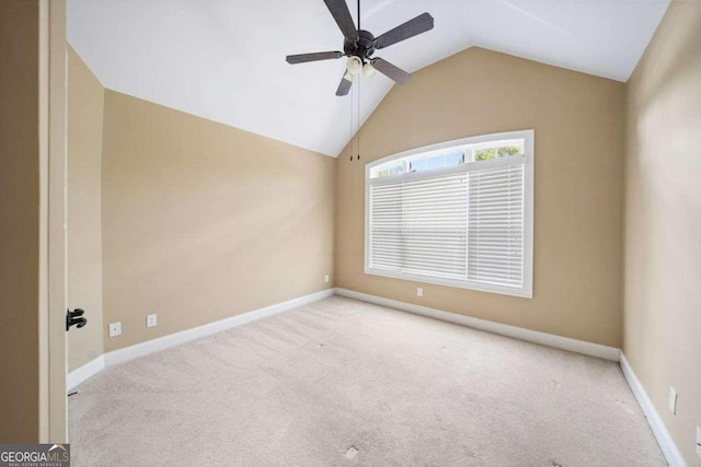 carpeted spare room featuring lofted ceiling, a ceiling fan, and baseboards