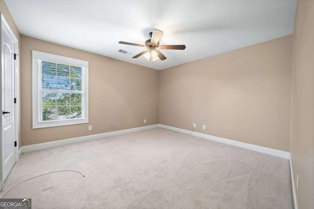 carpeted empty room featuring visible vents, a ceiling fan, and baseboards