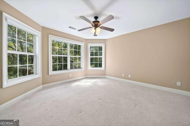 empty room featuring baseboards, a ceiling fan, visible vents, and a wealth of natural light