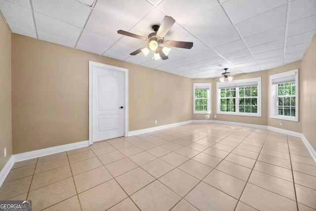 tiled empty room featuring a drop ceiling, plenty of natural light, and ceiling fan