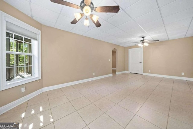 empty room with ceiling fan, light tile patterned flooring, and a drop ceiling