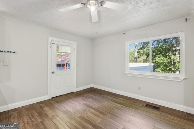 spare room with a textured ceiling, dark wood-type flooring, and ceiling fan