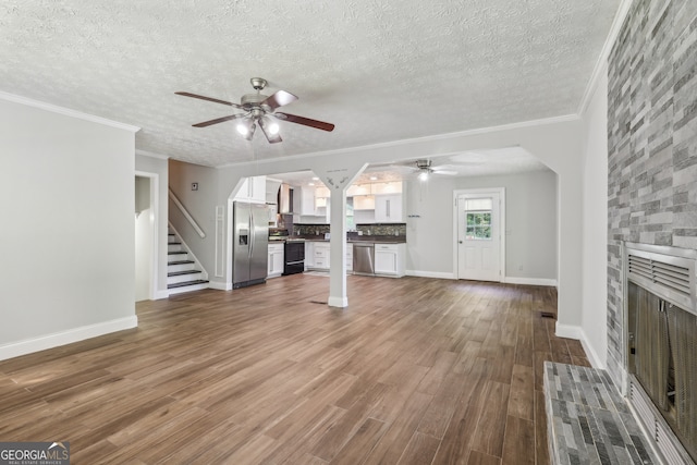 unfurnished living room featuring crown molding, hardwood / wood-style flooring, a textured ceiling, and ceiling fan