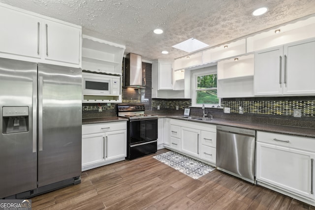 kitchen featuring appliances with stainless steel finishes, dark hardwood / wood-style floors, white cabinets, and wall chimney range hood