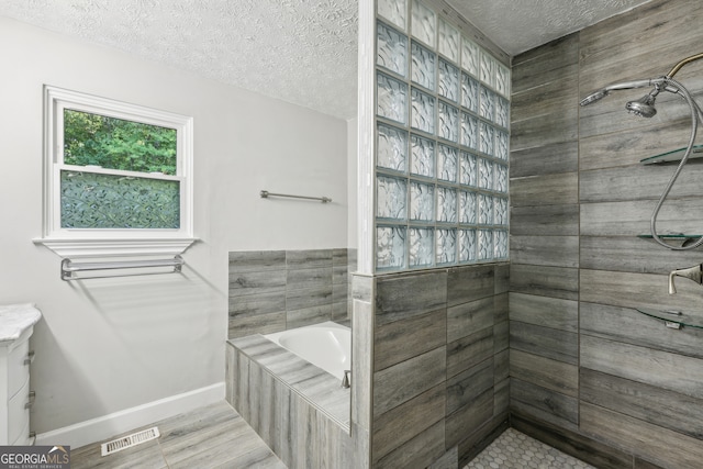 bathroom featuring hardwood / wood-style flooring, a textured ceiling, and separate shower and tub