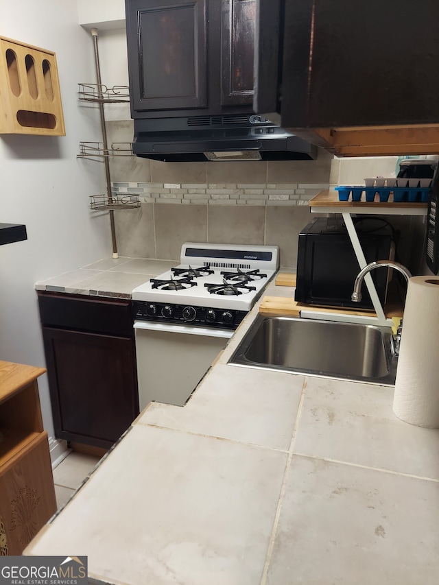 kitchen featuring dark brown cabinets, decorative backsplash, sink, and white range with gas stovetop