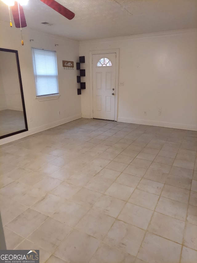 foyer entrance with ceiling fan, crown molding, and light tile patterned flooring