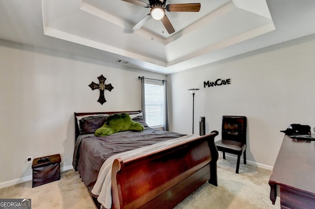 bedroom with a raised ceiling, ceiling fan, and light carpet