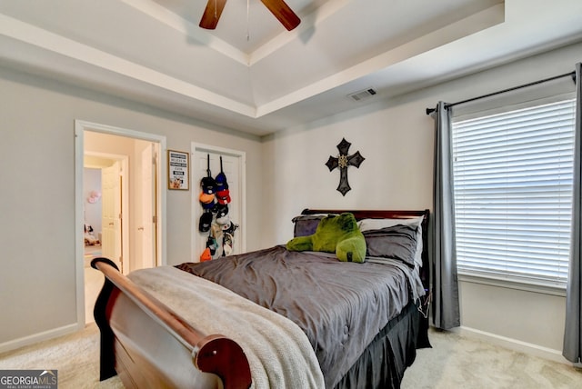 bedroom with a tray ceiling, ceiling fan, and light colored carpet