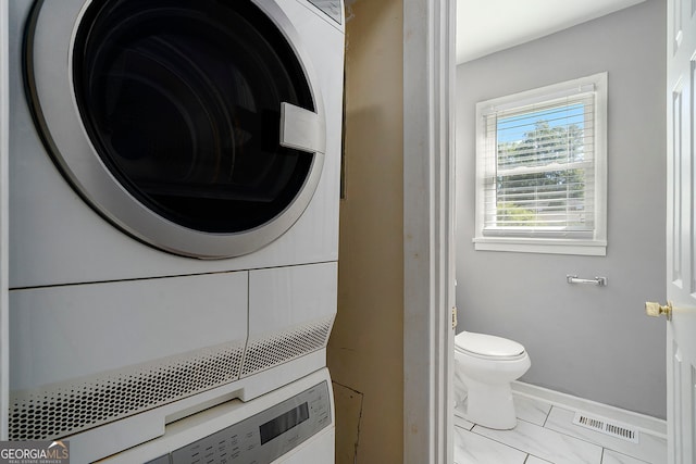 clothes washing area with stacked washer and clothes dryer