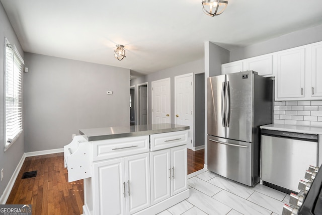 kitchen featuring white cabinets, appliances with stainless steel finishes, a center island, and decorative backsplash