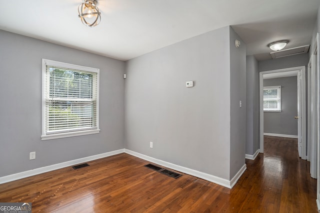 spare room with a healthy amount of sunlight and dark wood-type flooring