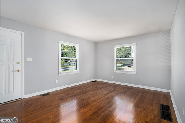 spare room featuring a healthy amount of sunlight and dark hardwood / wood-style flooring