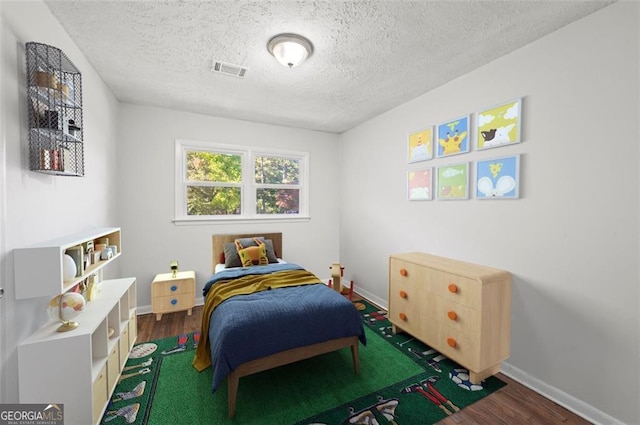 bedroom featuring dark hardwood / wood-style flooring and a textured ceiling