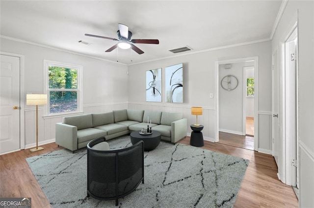 living room with light hardwood / wood-style flooring, ceiling fan, and crown molding