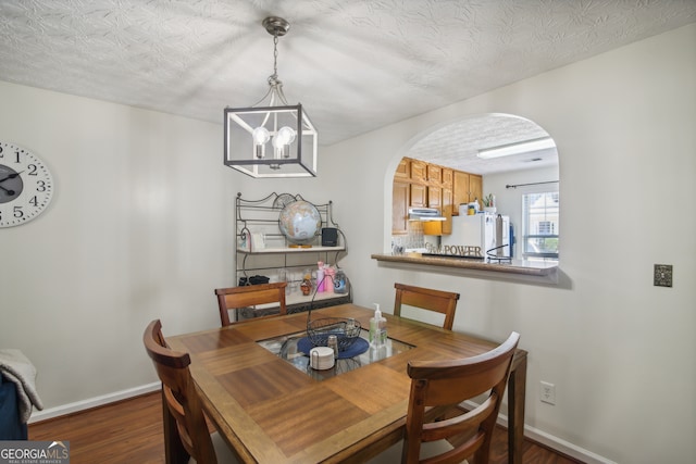 dining space featuring a chandelier, dark hardwood / wood-style flooring, and a textured ceiling