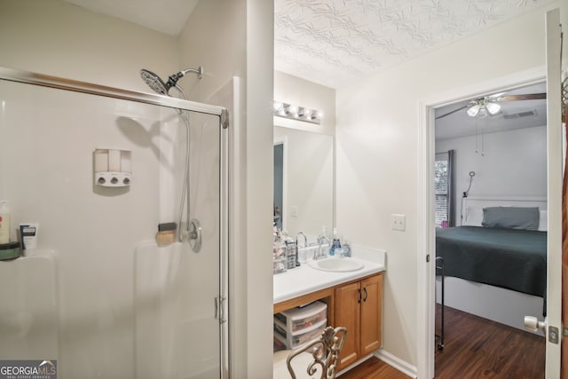 bathroom featuring ceiling fan, vanity, a shower with shower door, and hardwood / wood-style floors