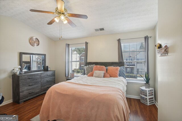 bedroom with multiple windows, ceiling fan, dark hardwood / wood-style floors, and a textured ceiling