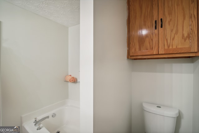 bathroom featuring toilet, a washtub, and a textured ceiling